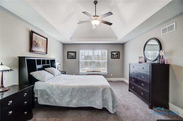 carpeted bedroom featuring lofted ceiling, a raised ceiling, and ceiling fan