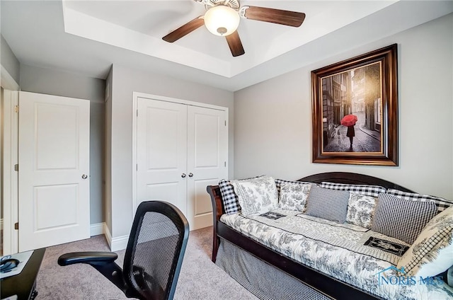 office with light carpet, a tray ceiling, and ceiling fan