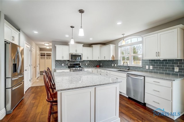 kitchen featuring sink, a center island, appliances with stainless steel finishes, pendant lighting, and white cabinets