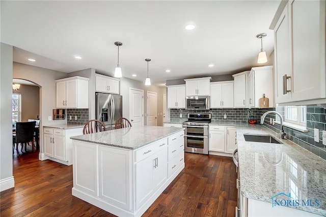 kitchen with sink, white cabinetry, a center island, pendant lighting, and stainless steel appliances