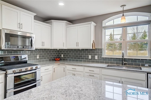 kitchen featuring sink, backsplash, stainless steel appliances, and white cabinets