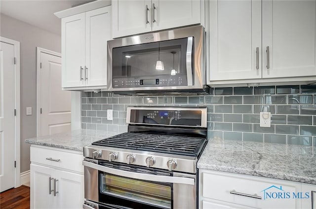 kitchen with dark wood-type flooring, stainless steel appliances, light stone countertops, decorative backsplash, and white cabinets