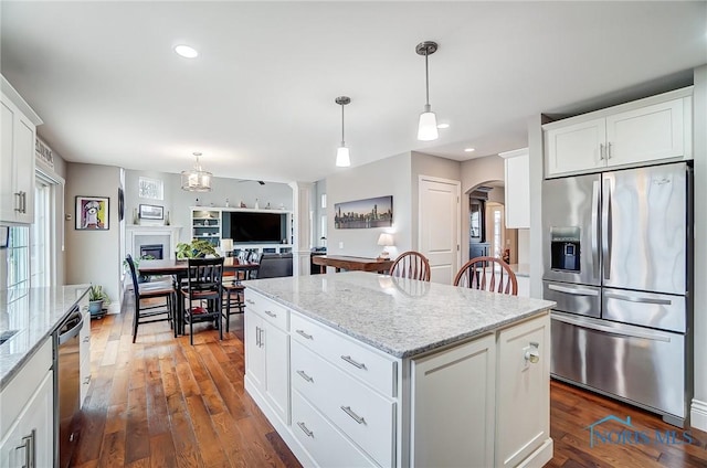 kitchen with decorative light fixtures, stainless steel appliances, a center island, and white cabinets