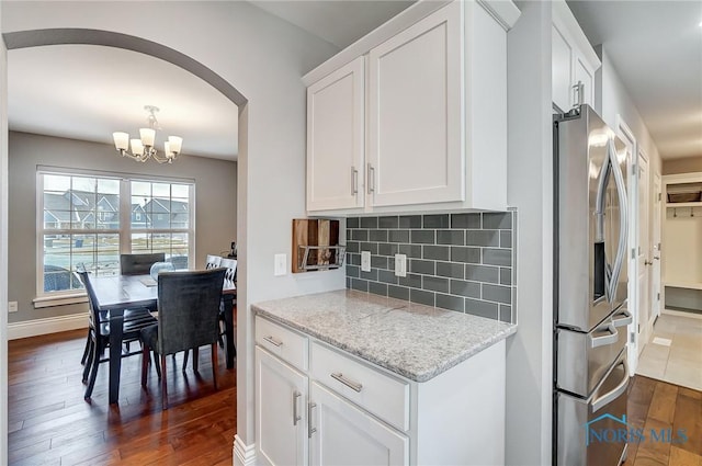 kitchen with white cabinetry, dark hardwood / wood-style floors, light stone counters, tasteful backsplash, and stainless steel fridge with ice dispenser