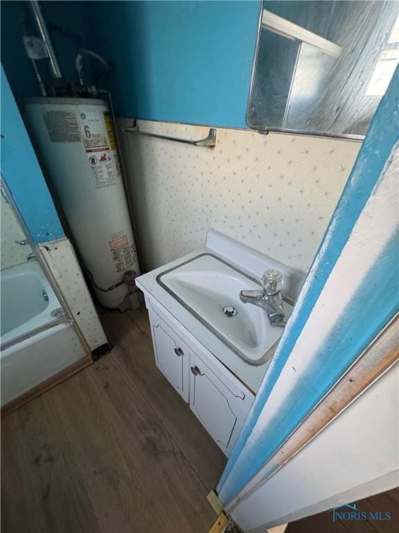 bathroom featuring vanity, hardwood / wood-style floors, and gas water heater