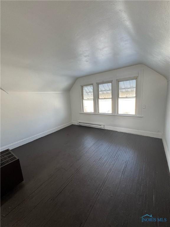 bonus room with dark wood-type flooring, a baseboard radiator, and vaulted ceiling