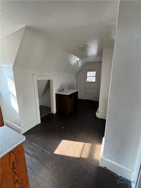 additional living space with vaulted ceiling and dark hardwood / wood-style flooring