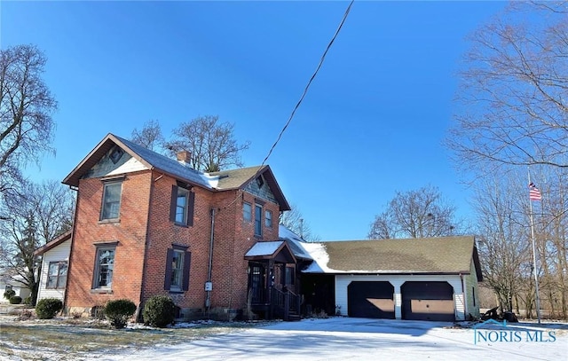 snow covered property with a garage