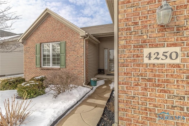 entrance to property with brick siding and roof with shingles