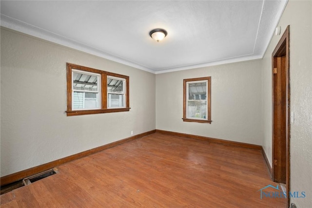 empty room featuring wood-type flooring and ornamental molding