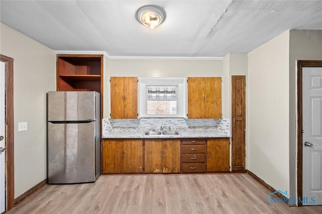 kitchen with stainless steel refrigerator, sink, decorative backsplash, and light wood-type flooring