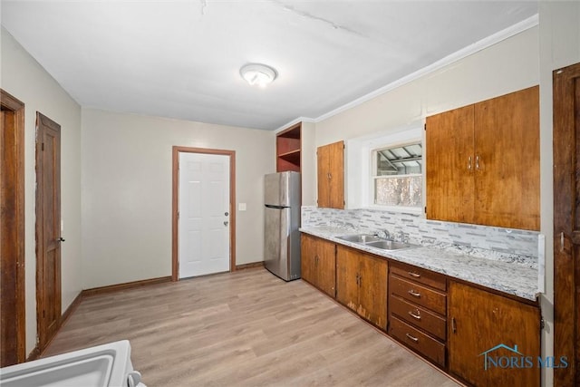 kitchen with tasteful backsplash, sink, stainless steel fridge, ornamental molding, and light hardwood / wood-style floors