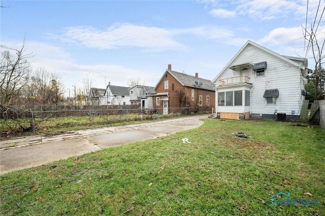 rear view of property featuring a balcony and a lawn