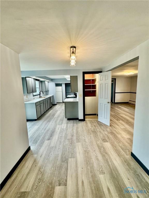 kitchen with sink, light hardwood / wood-style floors, hanging light fixtures, and gray cabinetry