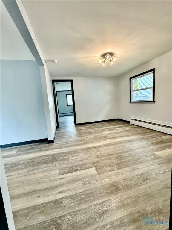 spare room with a baseboard radiator and light wood-type flooring