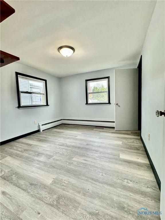 spare room with a baseboard radiator and light wood-type flooring