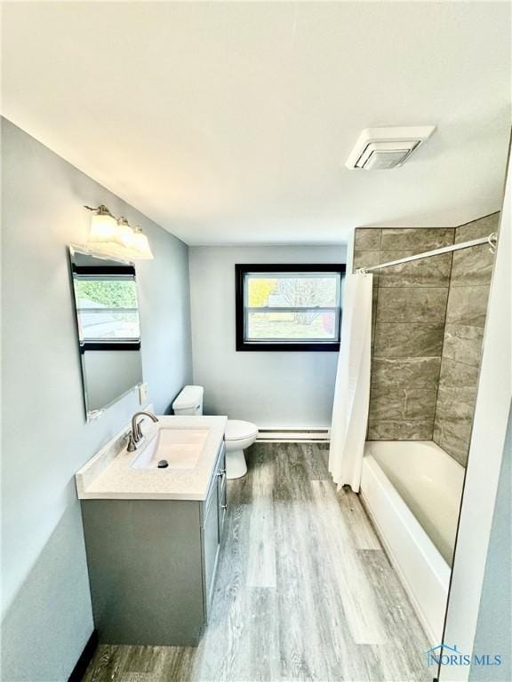 full bathroom featuring baseboard heating, shower / tub combo, hardwood / wood-style floors, vanity, and toilet