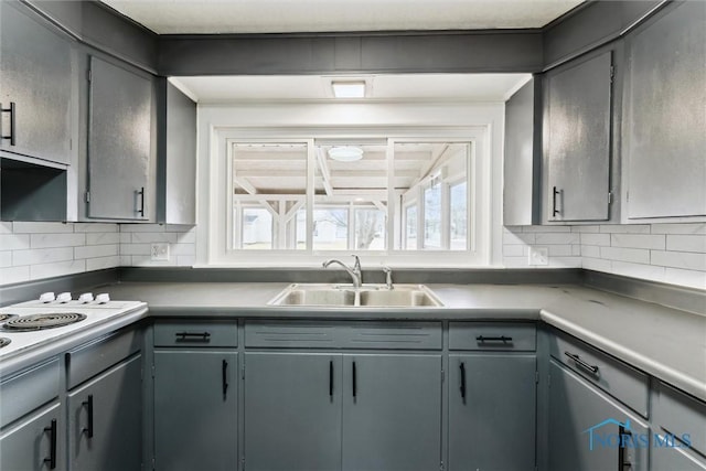 kitchen with decorative backsplash, gray cabinets, and a sink