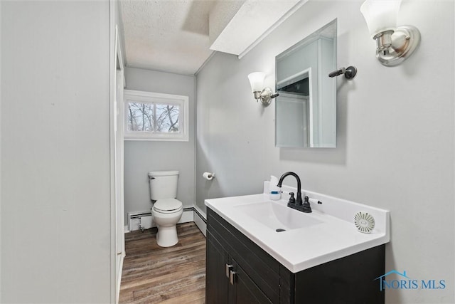 bathroom featuring toilet, wood finished floors, baseboard heating, a textured ceiling, and vanity