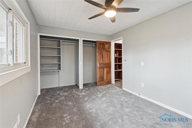 unfurnished bedroom with baseboards, ceiling fan, carpet, and multiple closets