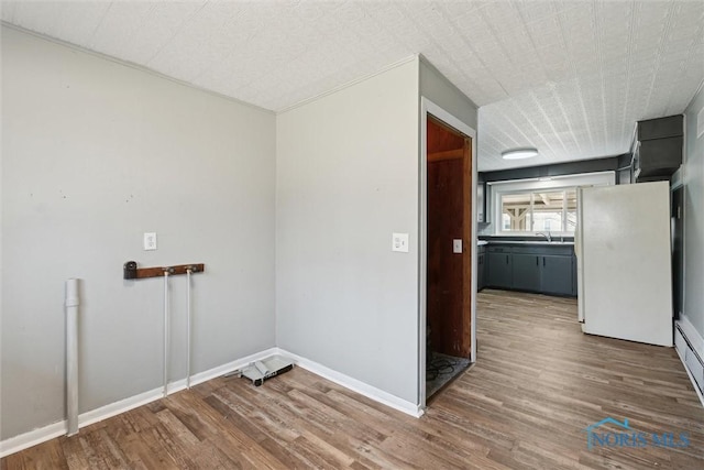 laundry area featuring a sink, baseboards, and wood finished floors