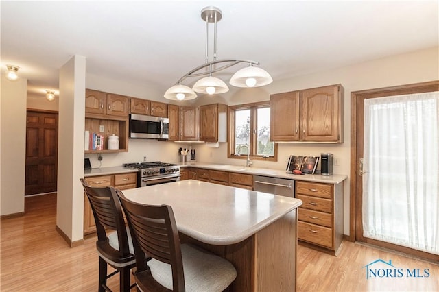 kitchen featuring sink, a center island, hanging light fixtures, stainless steel appliances, and light hardwood / wood-style floors