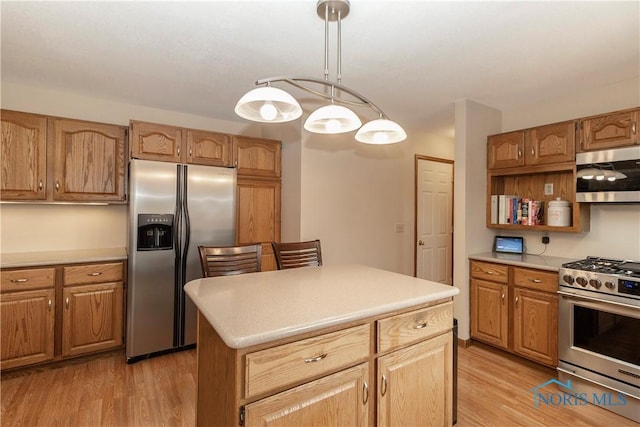 kitchen featuring stainless steel appliances, hanging light fixtures, a center island, and light wood-type flooring