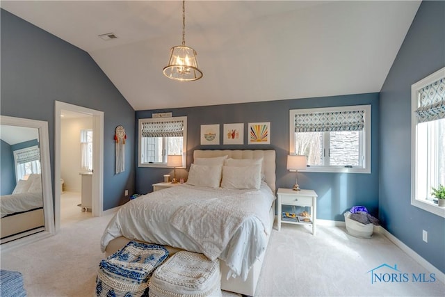 bedroom featuring an inviting chandelier, ensuite bath, carpet flooring, and vaulted ceiling