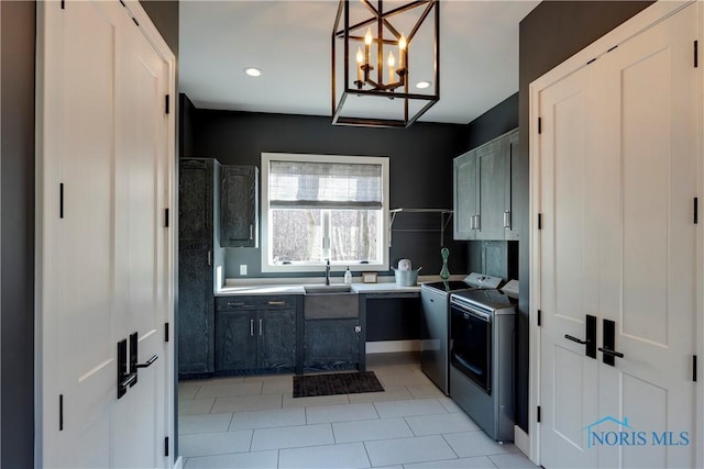 kitchen featuring sink, hanging light fixtures, light tile patterned floors, washing machine and dryer, and an inviting chandelier