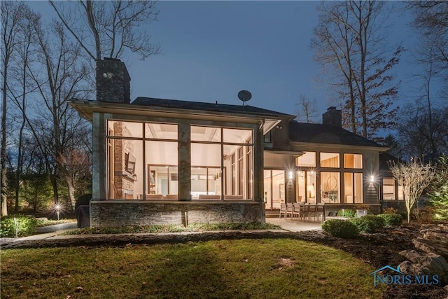 rear view of house featuring a yard, a patio area, and a sunroom