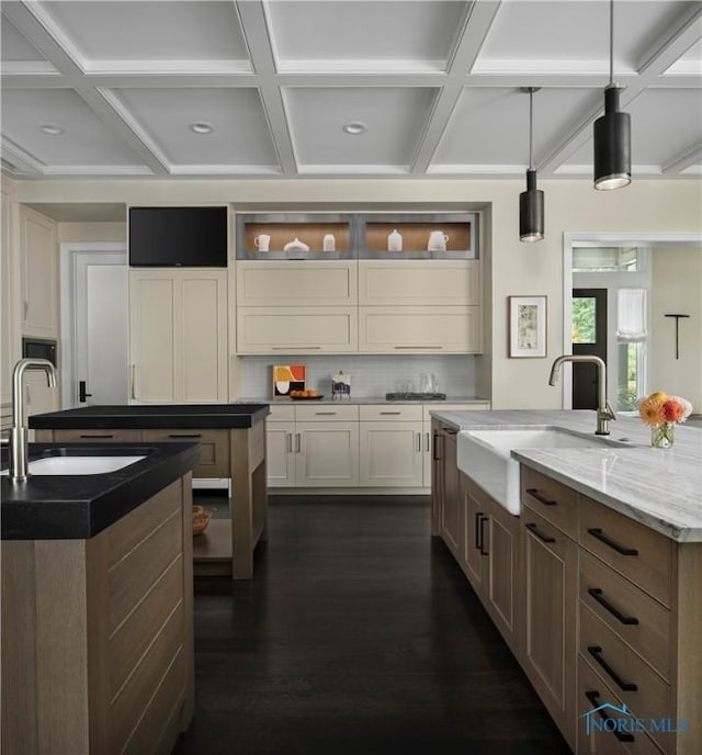 kitchen featuring hanging light fixtures, light stone countertops, sink, and a large island