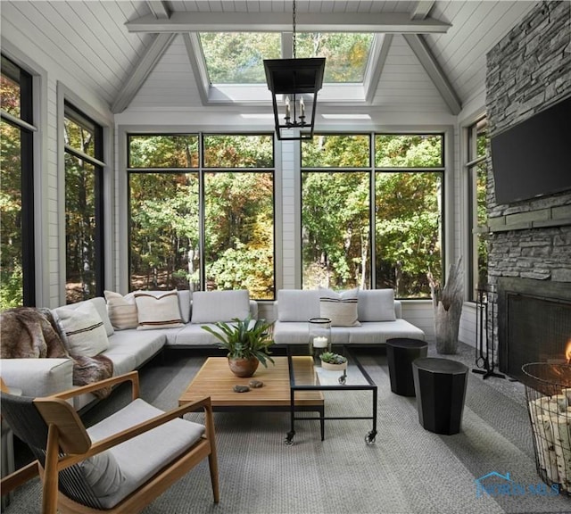 sunroom with lofted ceiling with skylight, a notable chandelier, and a fireplace