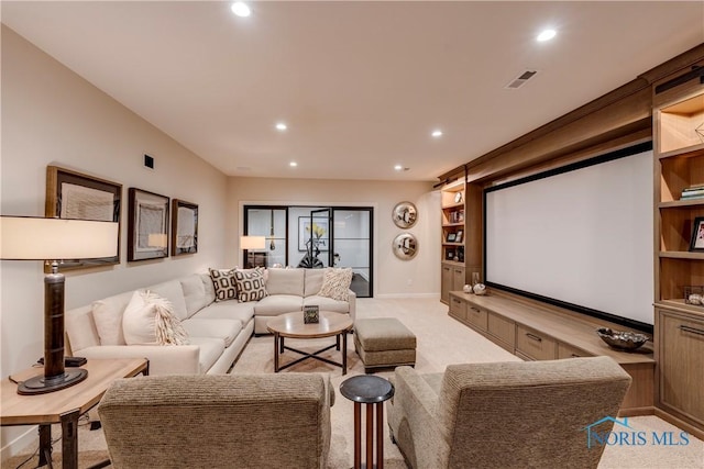 home theater room with light colored carpet and built in features