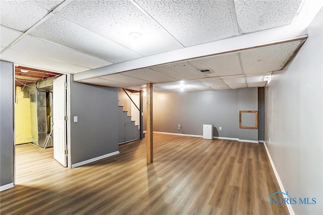 basement with a paneled ceiling and hardwood / wood-style floors