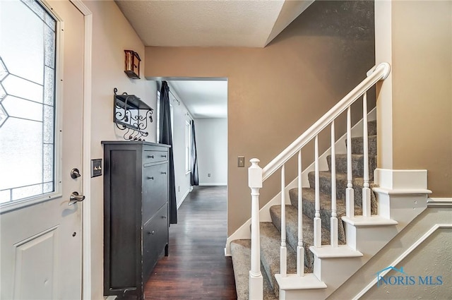 foyer entrance with a textured ceiling and dark hardwood / wood-style flooring