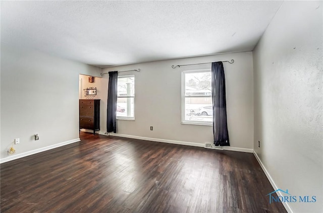 unfurnished room with dark hardwood / wood-style floors and a textured ceiling