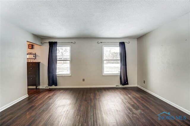 unfurnished room featuring a wealth of natural light, dark hardwood / wood-style floors, and a textured ceiling