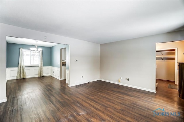 empty room with an inviting chandelier and dark wood-type flooring