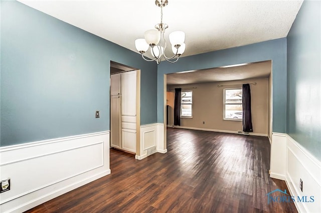 empty room featuring an inviting chandelier and dark hardwood / wood-style floors