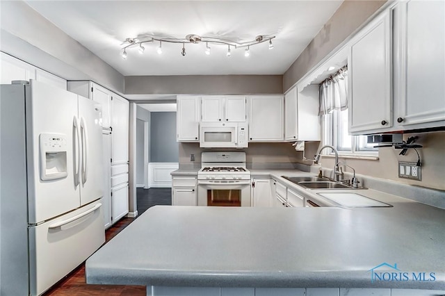 kitchen featuring white appliances, kitchen peninsula, sink, and white cabinets