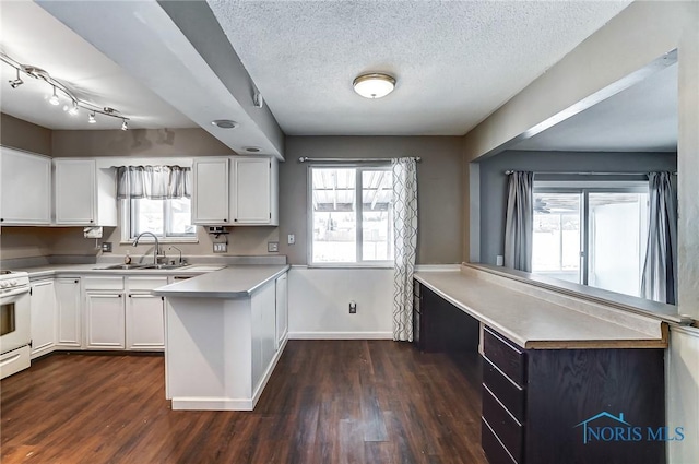 kitchen with dark hardwood / wood-style floors, white cabinetry, sink, kitchen peninsula, and a textured ceiling