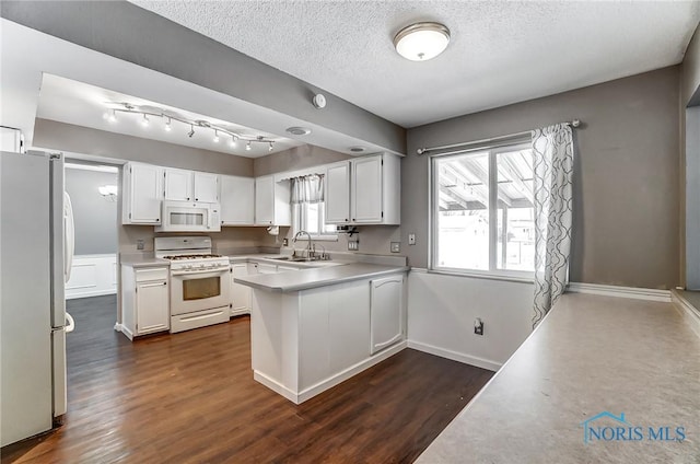 kitchen with white appliances, plenty of natural light, sink, and white cabinets