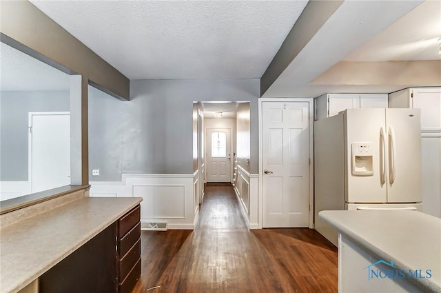 kitchen with white cabinetry, white fridge with ice dispenser, a textured ceiling, and dark hardwood / wood-style flooring