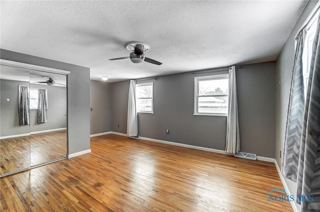 unfurnished bedroom featuring hardwood / wood-style flooring, ceiling fan, a textured ceiling, and a closet