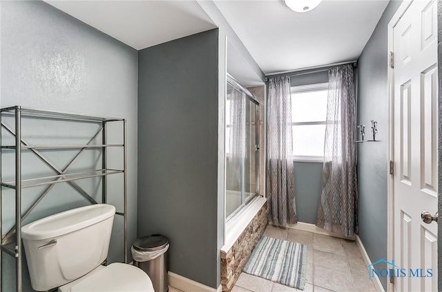 bathroom with tile patterned flooring, toilet, and combined bath / shower with glass door