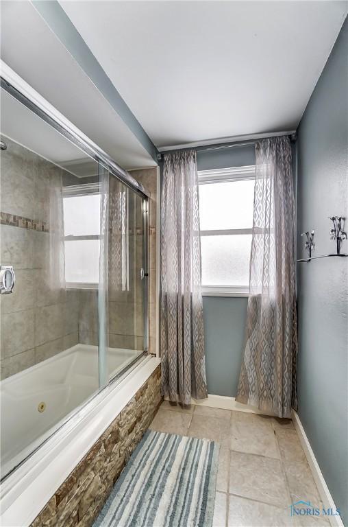 bathroom with tile patterned flooring, plenty of natural light, and enclosed tub / shower combo