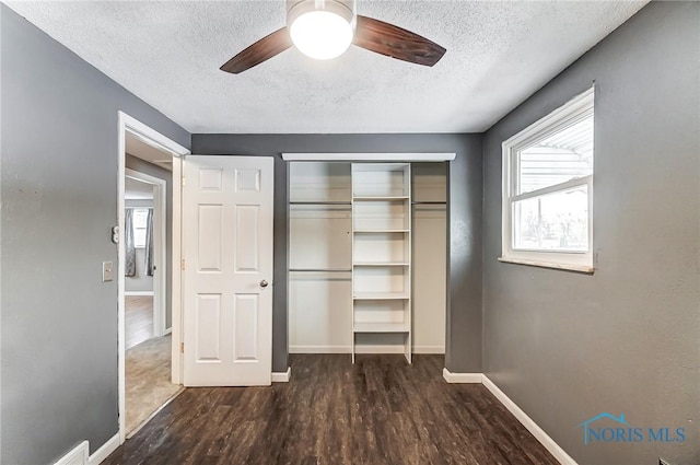 unfurnished bedroom featuring dark hardwood / wood-style flooring, a textured ceiling, a closet, and ceiling fan