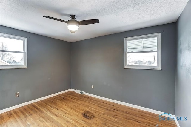 empty room with wood-type flooring, ceiling fan, and a textured ceiling