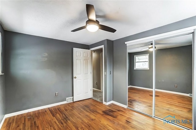 unfurnished bedroom with ceiling fan, wood-type flooring, and a closet