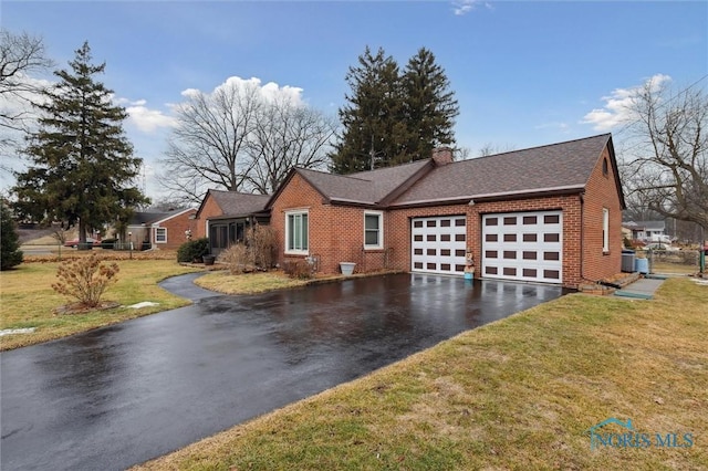 single story home with driveway, a garage, a chimney, a front lawn, and brick siding